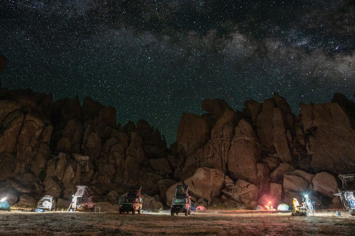 The camp at night with a rocky landscape in the background