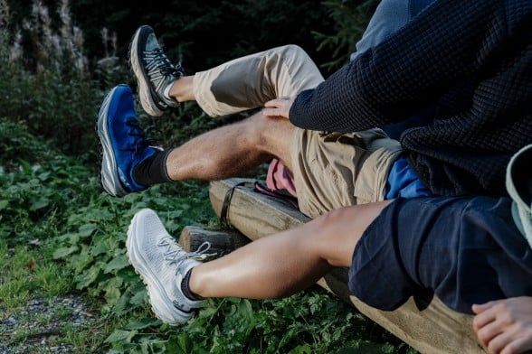 Two hikers from behind with packs on their backs, walking across a wooden&nbsp;bridge